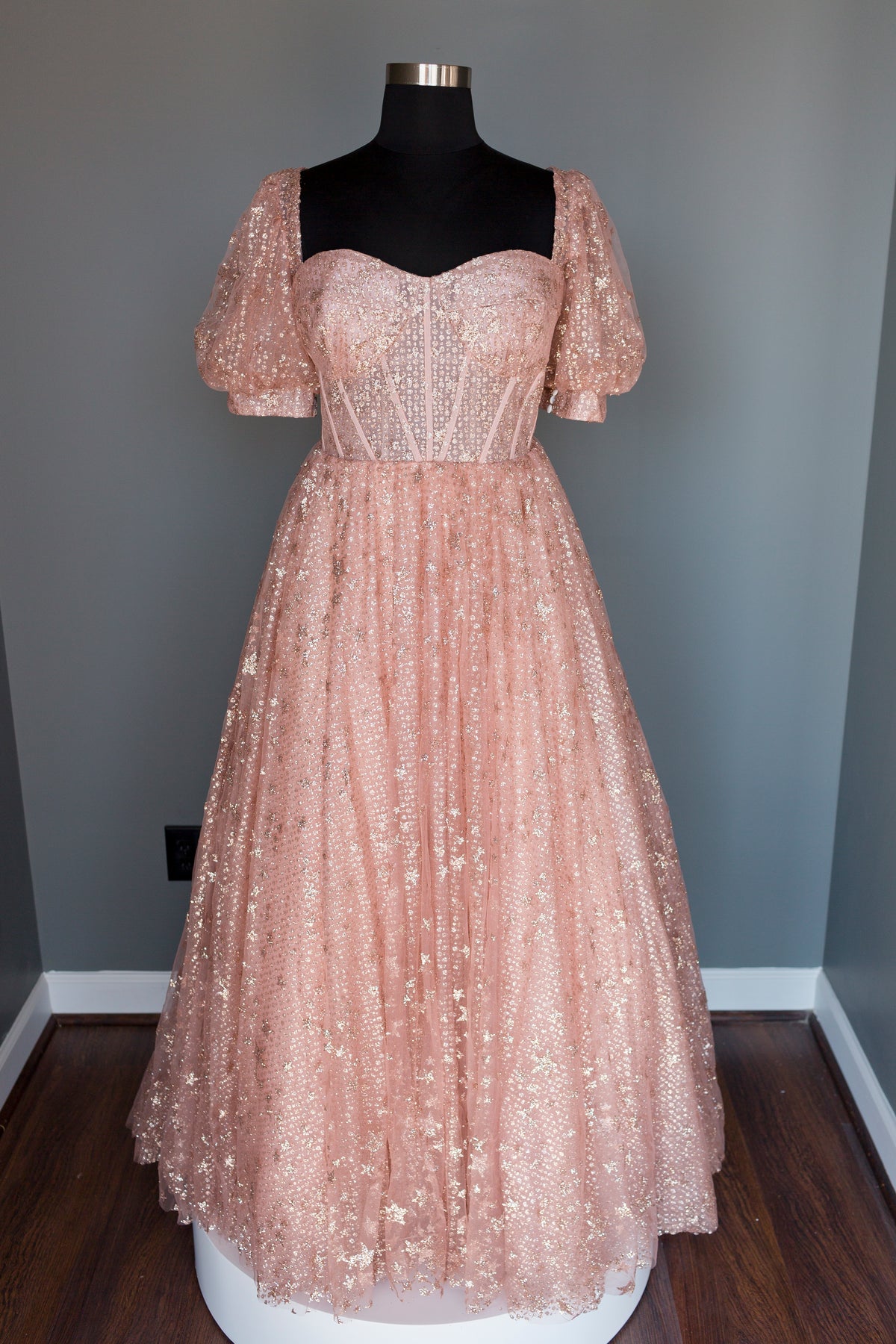 Sparkling blush wedding dress with puff sleeves and corset bodice, perfect for romantic celebrations.