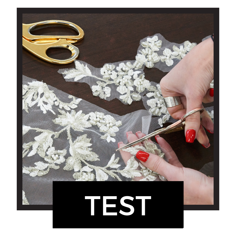 Hand cutting floral lace fabric with gold scissors for custom wedding dress design