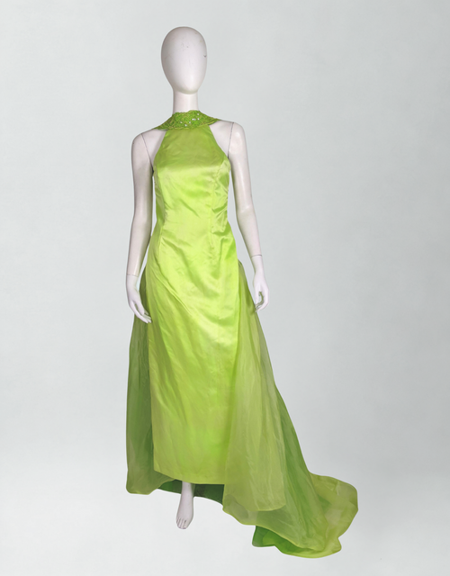 Mannequin wearing a bright green evening gown on a white background
