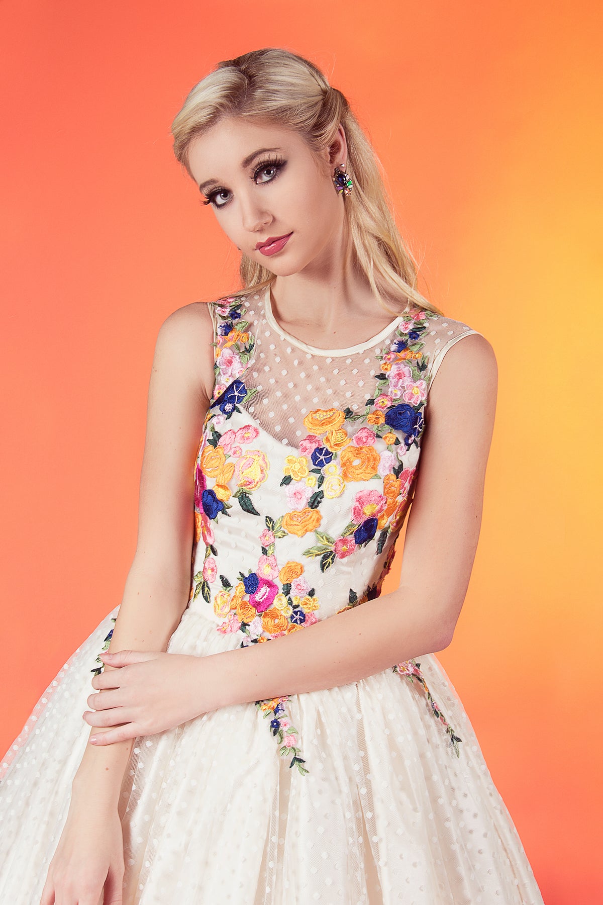 Bride in custom floral embroidered wedding dress with polka dot overlay, vibrant ombre background