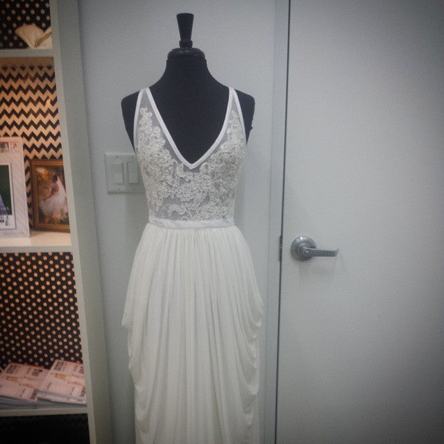 Elegant white lace wedding dress with V-neck and flowing skirt displayed on mannequin