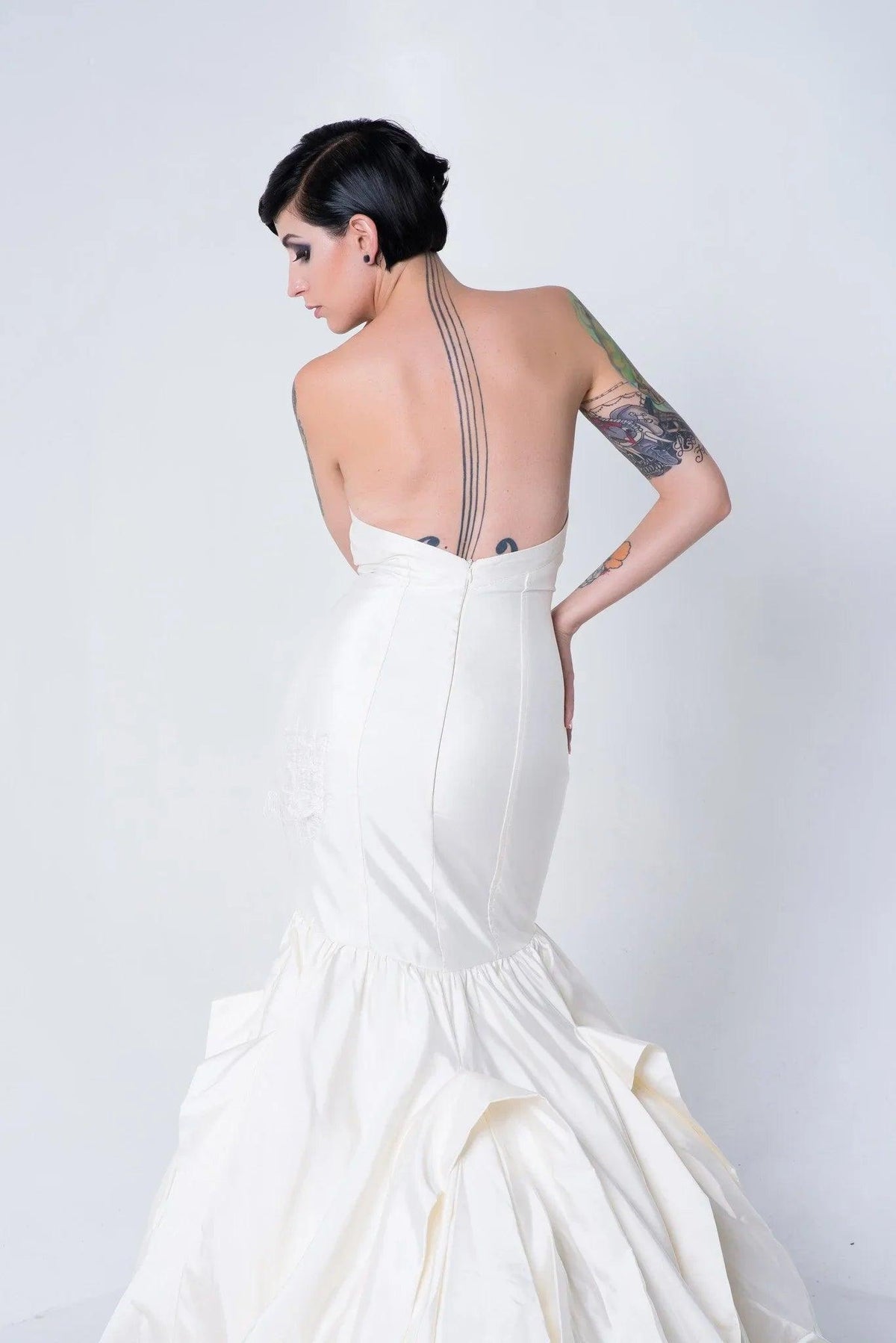 Strapless mermaid wedding dress with open back, showcasing tattoos and elegant silhouette