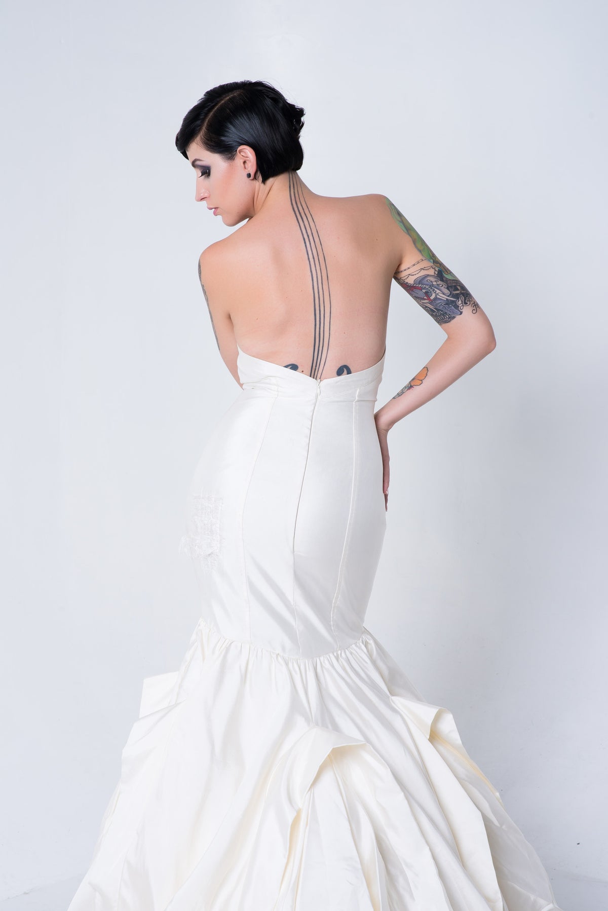 Strapless mermaid wedding dress with open back, showcasing tattoos and elegant silhouette