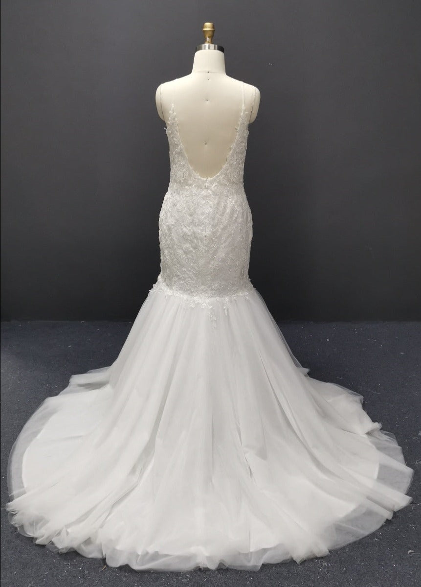 Elegant white mermaid wedding dress with lace detailing and open back, displayed on mannequin