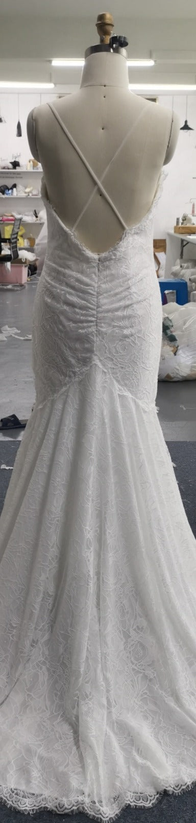 Elegant lace wedding dress with crisscross back, displayed on mannequin in studio