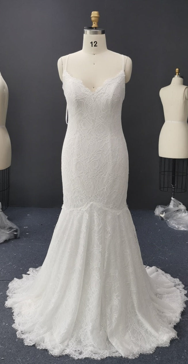 White lace mermaid wedding dress on mannequin, featuring V-neck and flared train for custom bridal design