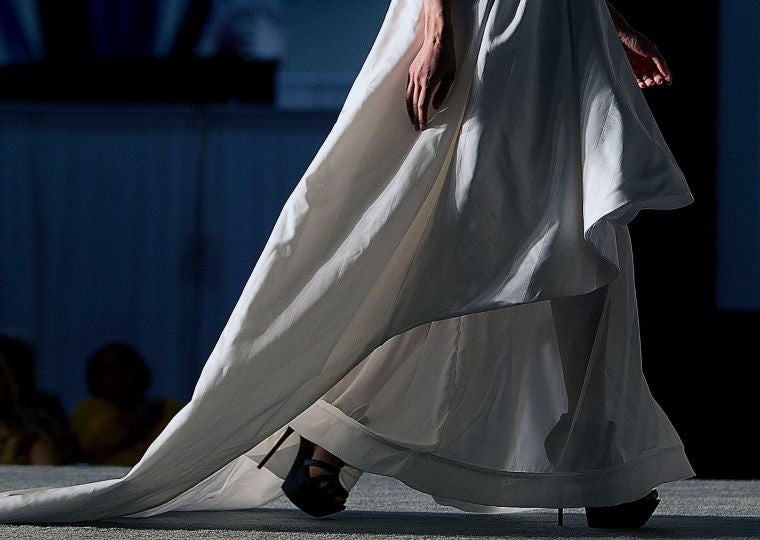 Elegant white wedding dress with flowing train and black heels, showcasing luxury bridal design.