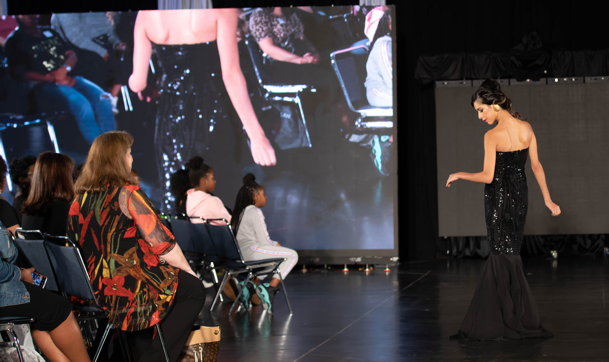 Model showcases black sequined mermaid gown on runway at bridal fashion show