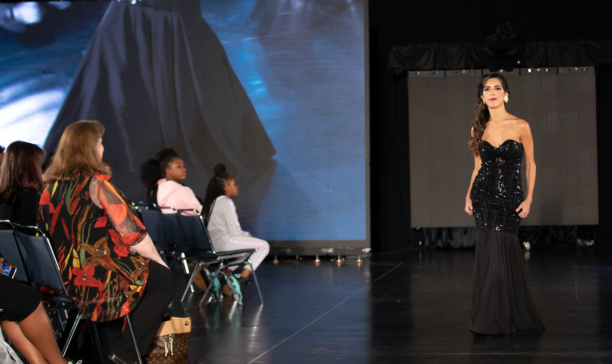Model showcasing black sequined strapless gown on runway at bridal fashion show
