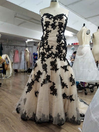 Black lace appliqué mermaid wedding dress on mannequin in design studio, custom bridal gown