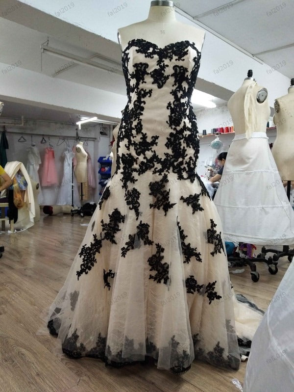 Black lace appliqué mermaid wedding dress on mannequin in design studio, custom bridal gown