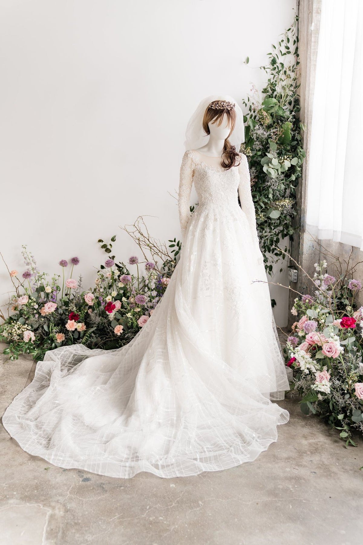 Elegant lace wedding dress with long sleeves and floral backdrop for custom bridal design