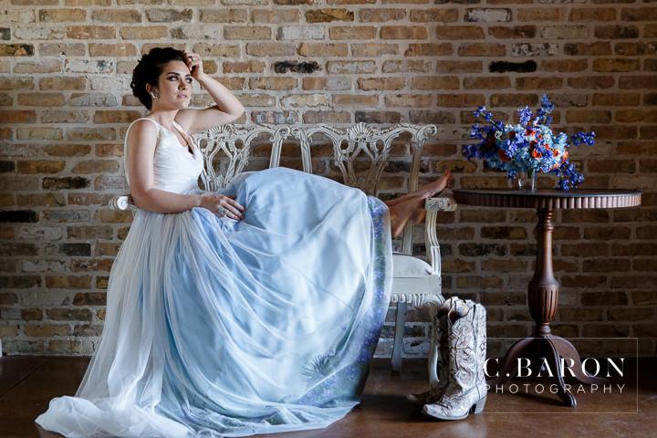 Bride in custom ombre blue wedding dress with cowboy boots, rustic brick backdrop