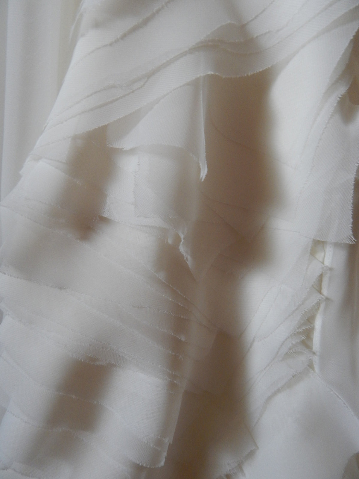 Elegant white wedding dress fabric with layered ruffles and soft texture