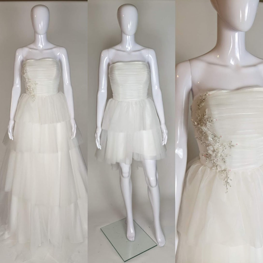 Strapless ivory wedding dress with tiered tulle skirt and floral beading, shown on mannequin