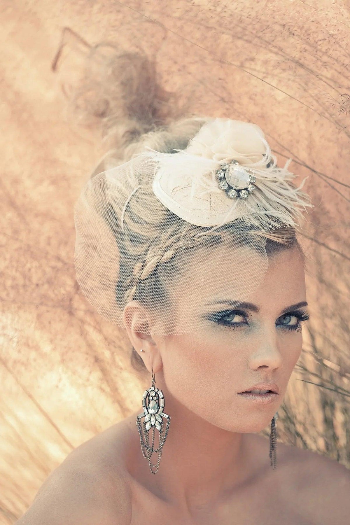 Elegant bridal headpiece with feathers and crystals, paired with statement earrings for a chic wedding look.