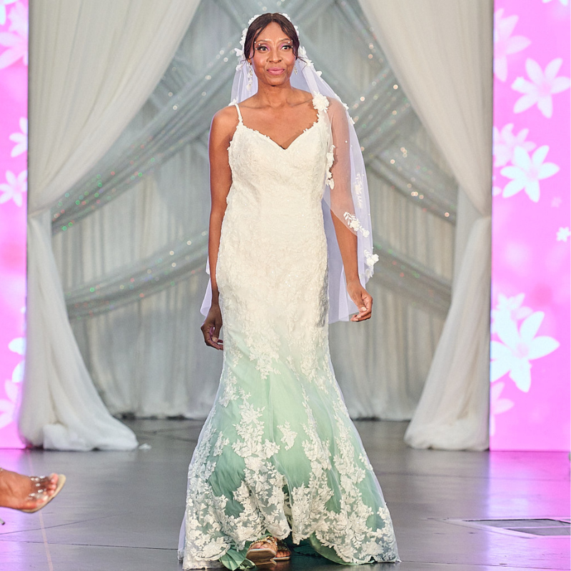 Bride in custom lace wedding dress with mint ombre dye, sheer veil, and floral details on runway