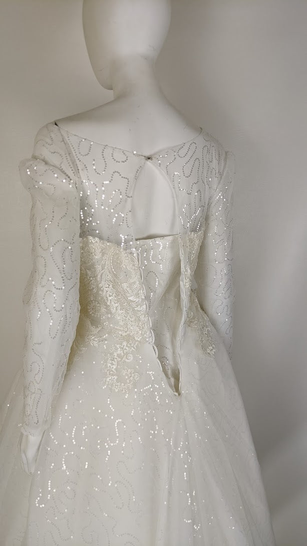Elegant white wedding dress with sequin detailing and long sleeves, showcasing intricate back design.