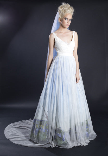 Elegant white wedding dress with floral hem, sheer veil, and flowing tulle skirt for modern bridal style