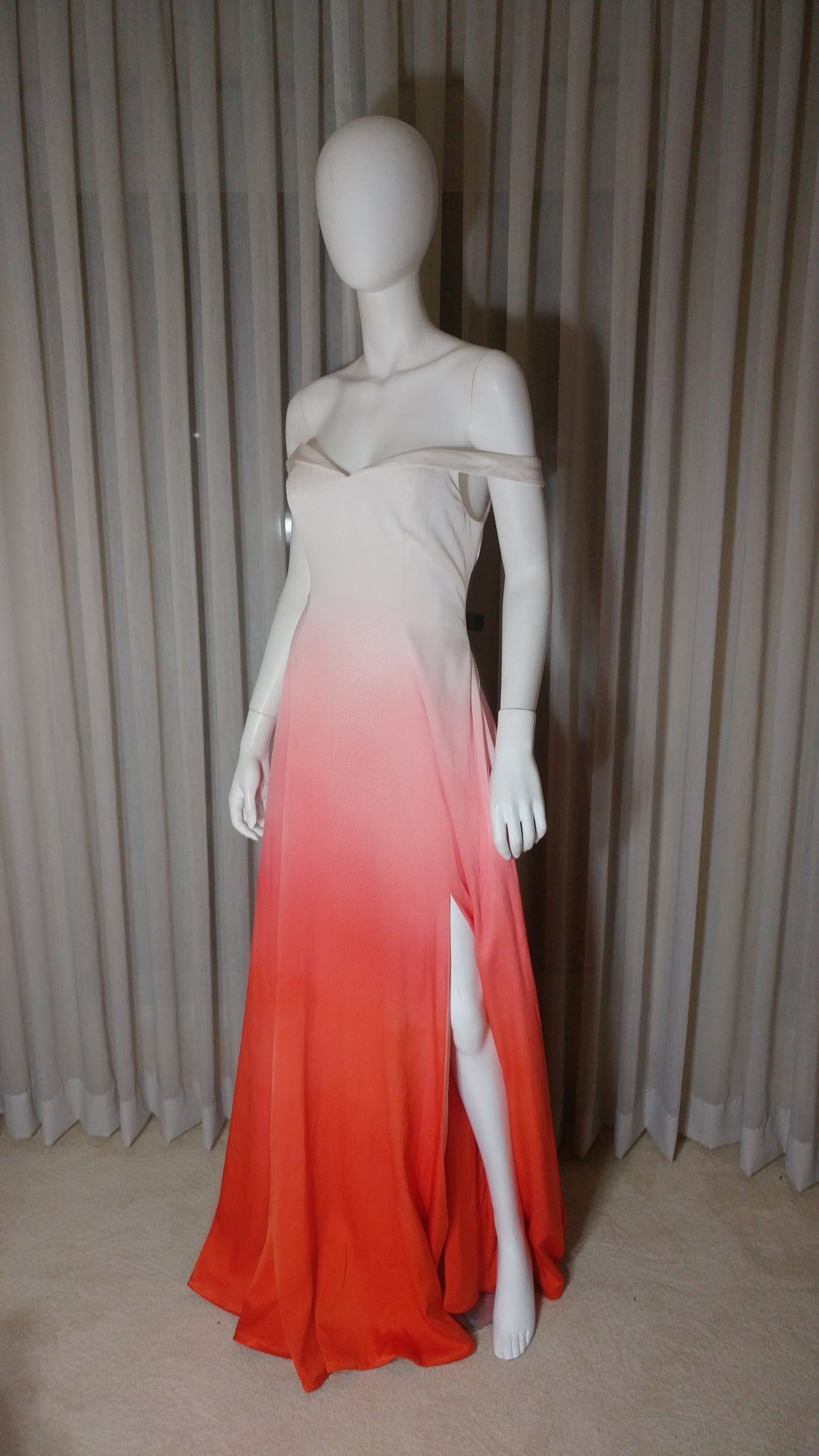Ombre wedding dress with off-shoulder design and high slit, transitioning from cream to vibrant orange.