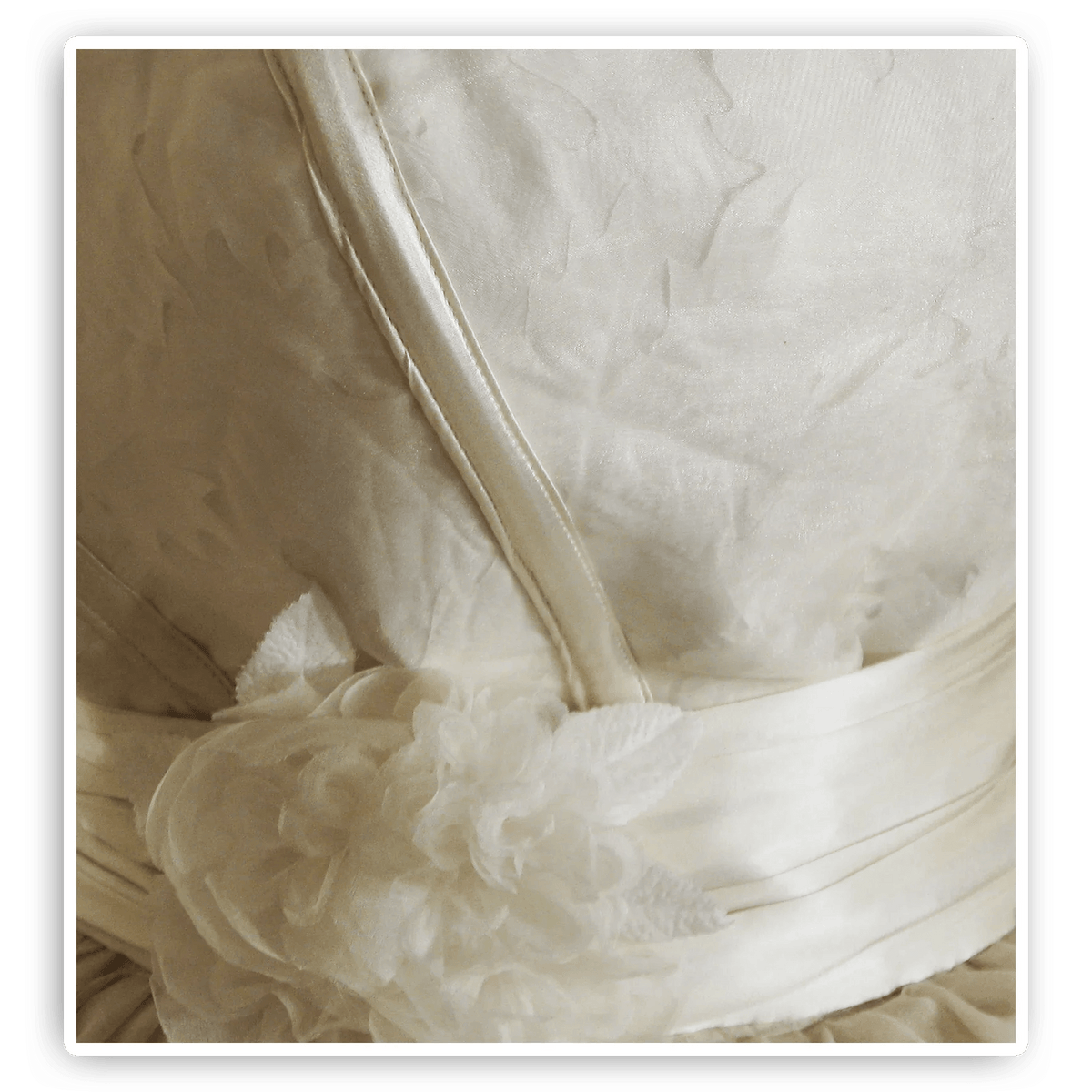 Elegant white wedding dress with floral detail and satin ribbon waistband