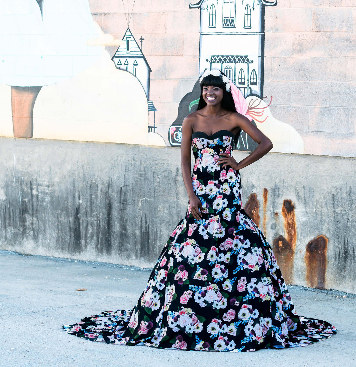 Floral black wedding dress with strapless design, vibrant blooms, and a dramatic train against mural backdrop.