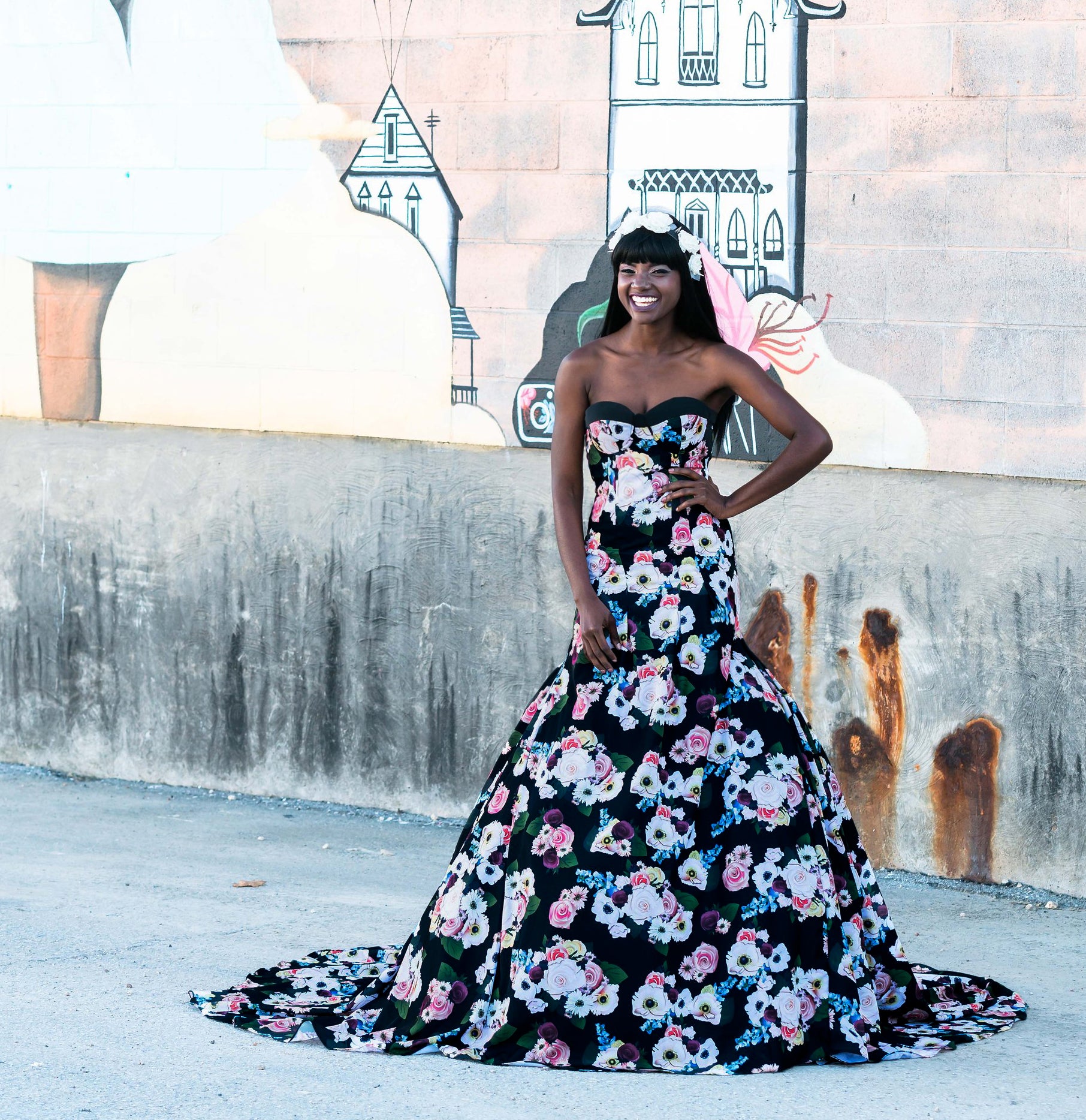 Floral black wedding dress with strapless design, vibrant blooms, and a dramatic train against mural backdrop.