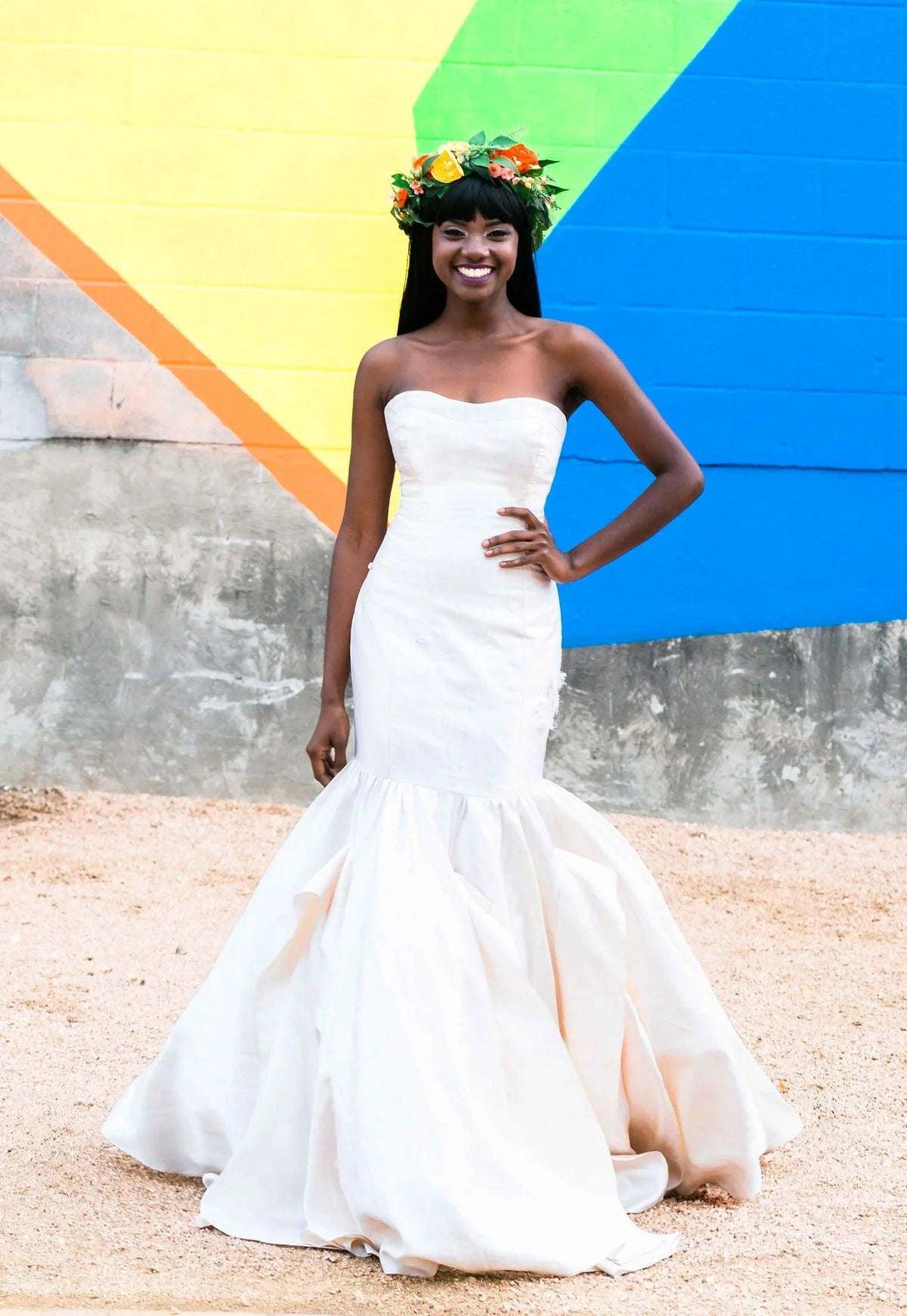 Bride in strapless mermaid wedding dress with floral crown against colorful mural