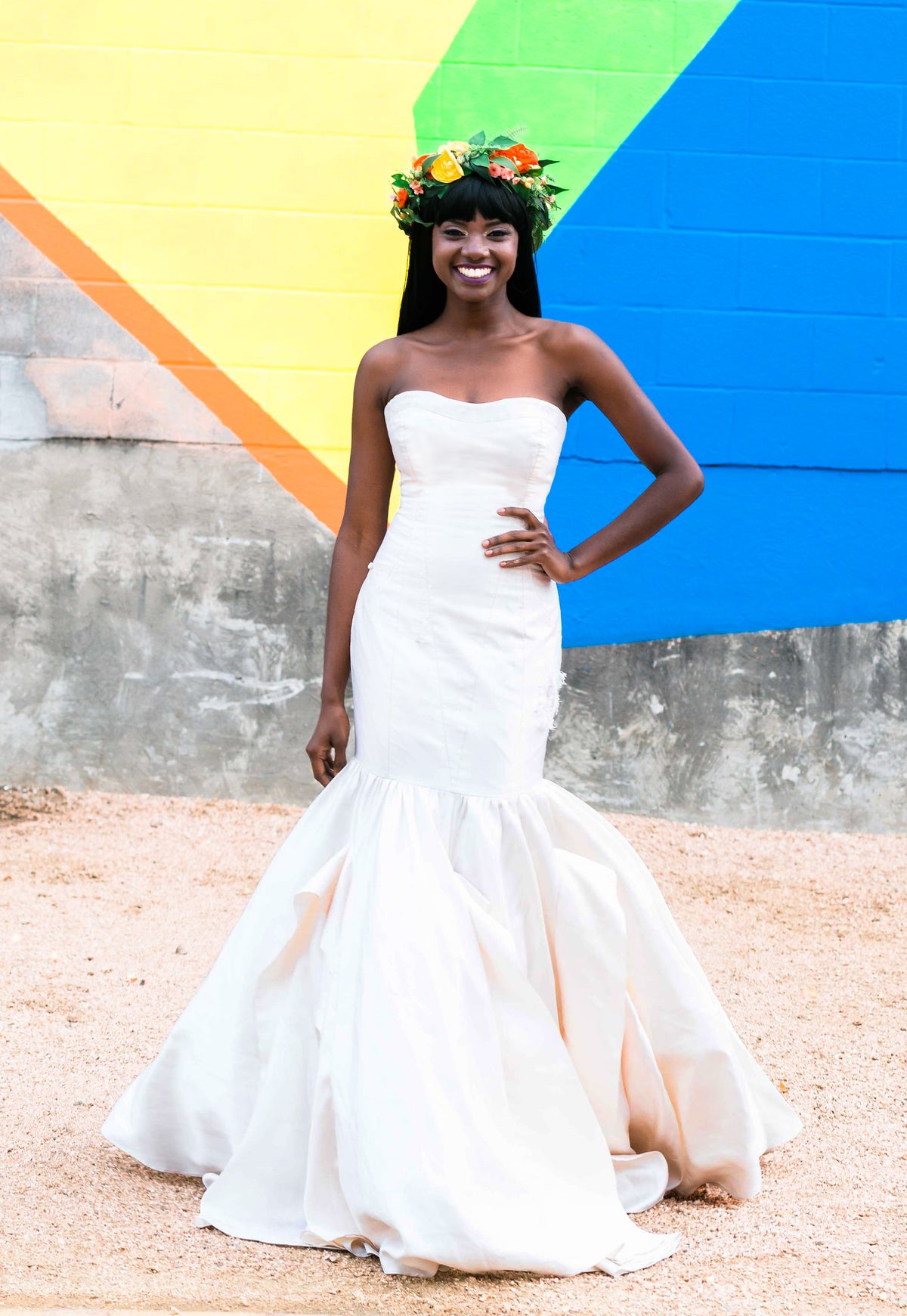 Bride in strapless mermaid wedding dress with floral crown against colorful mural