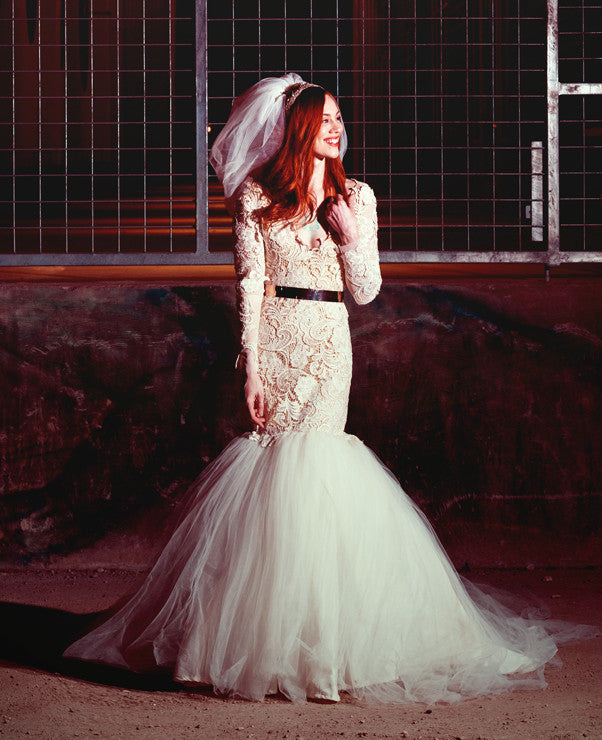 Bride in lace mermaid wedding dress with tulle skirt, black belt, and veil, styled for edgy bridal look