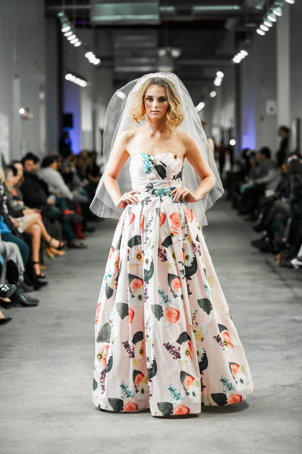Bride in floral strapless wedding gown with veil on runway